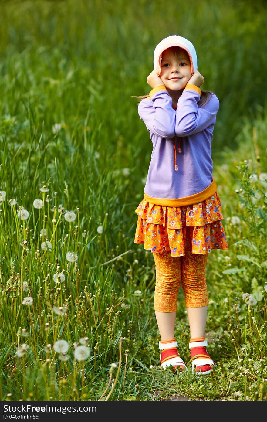 Pretty smiling girl in a hat full length on the green grass