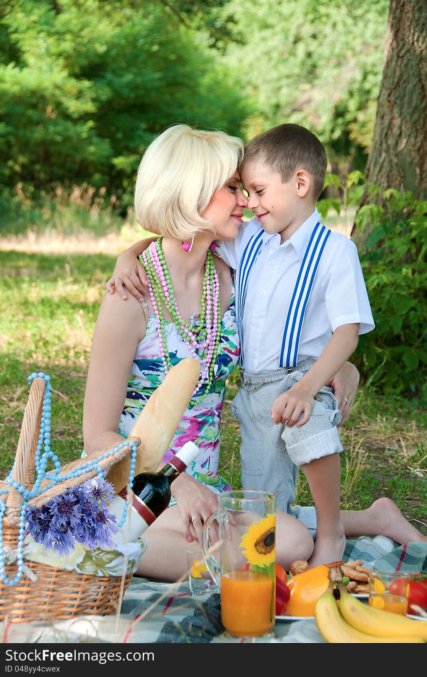 Happy family on a picnic. The son embraces mother.