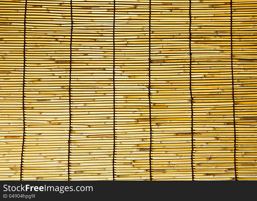 This is a wall of bamboo are woven together in a large sheet. This is a wall of bamboo are woven together in a large sheet.