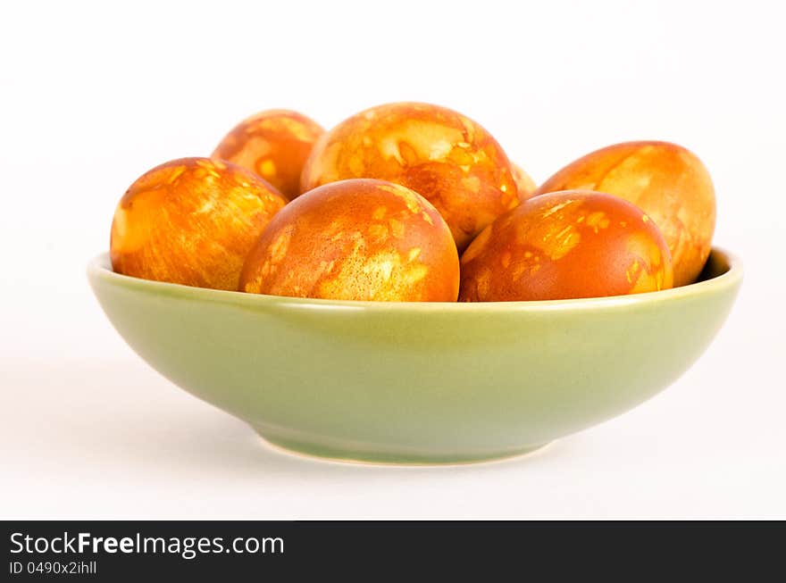 A green bowl holds naturally dyed golden marbled Easter eggs