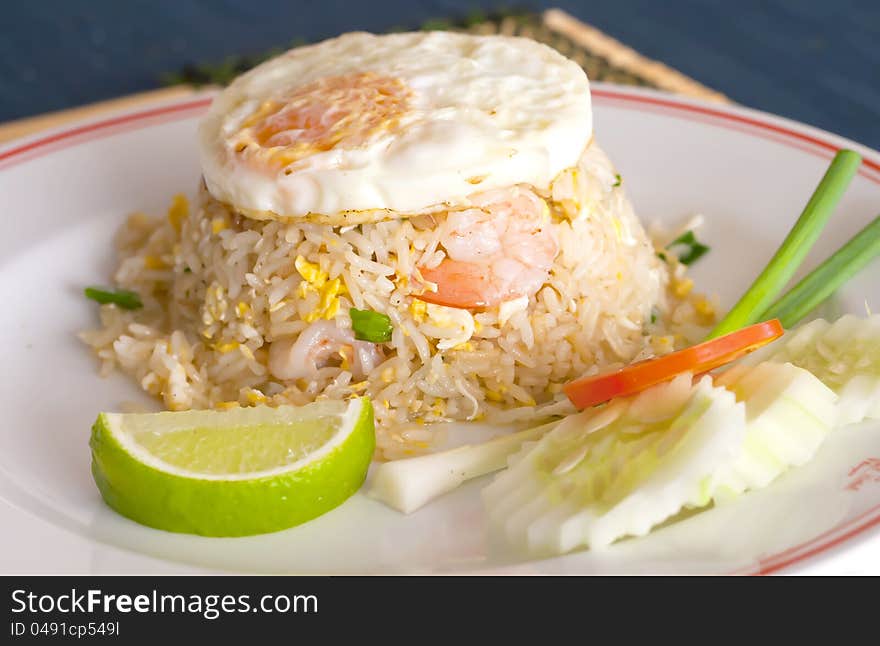 Shrimp fried rice and egg fired put topping on the dish with vegetables.