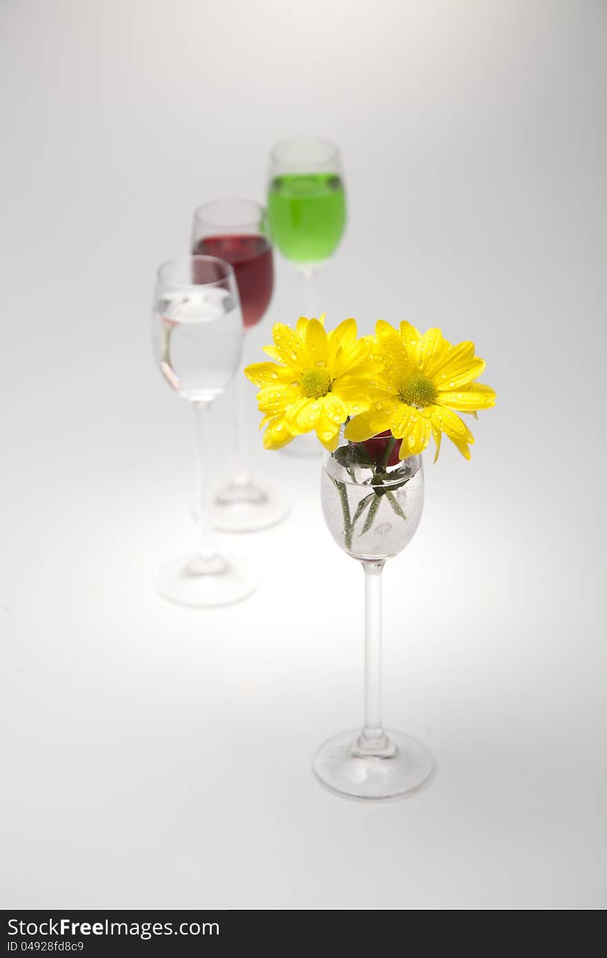 A Glass, Cherry And Yellow Flowers On A White Back