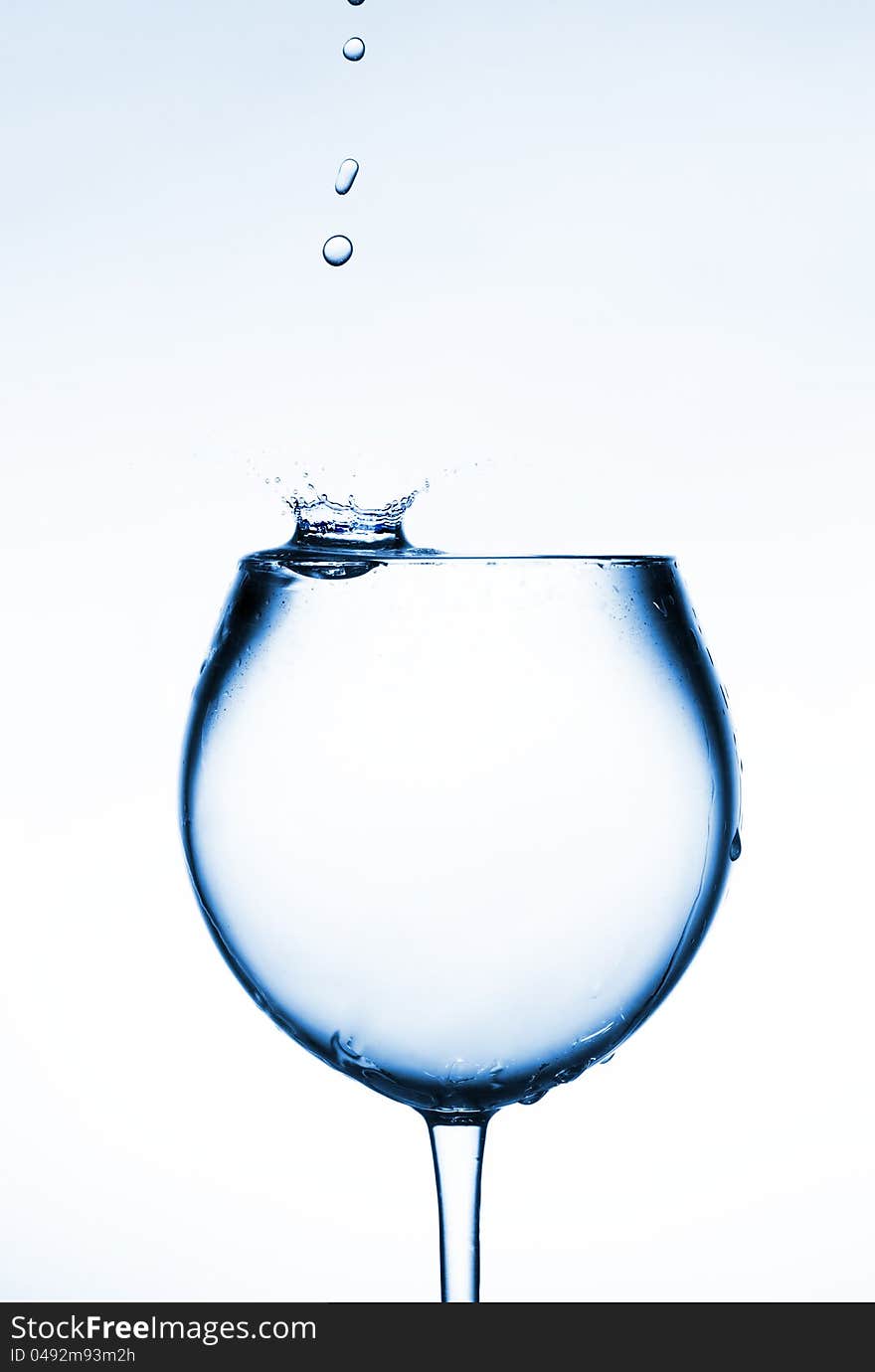 A glass of clear liquid and a drop falling into it. From the drop of fly spray.