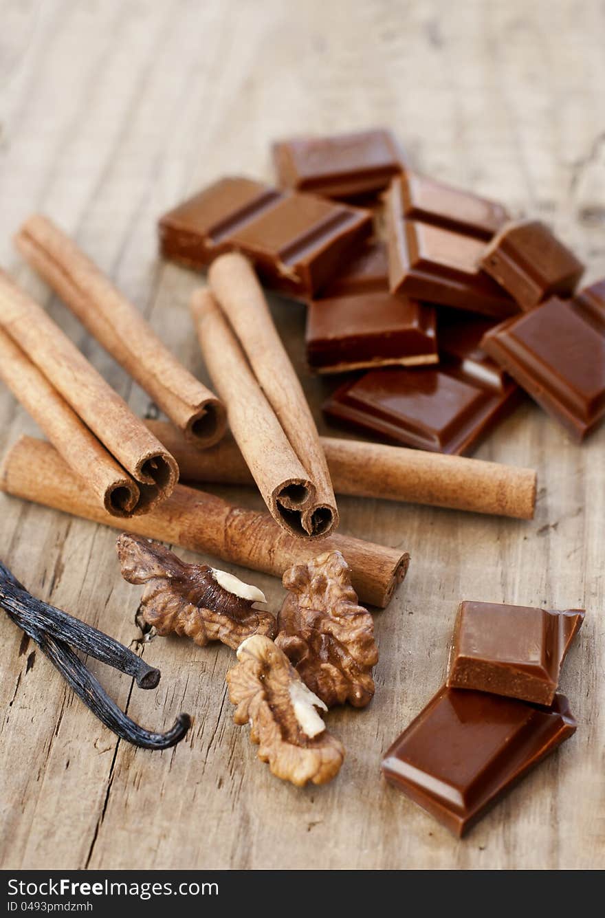 Confectionery products. Chocolate, cinnamon, walnuts and vanilla on wooden table. Confectionery products. Chocolate, cinnamon, walnuts and vanilla on wooden table