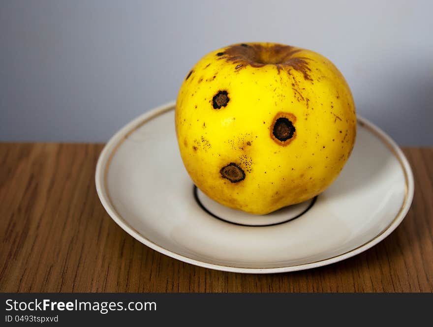 Bright yellow apple on white plate closeup. Bright yellow apple on white plate closeup