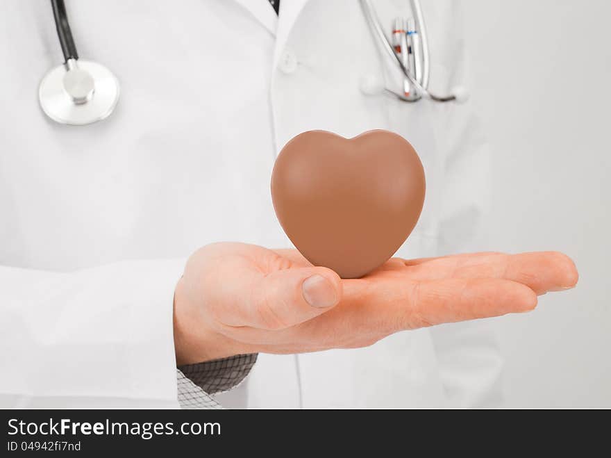 Doctor with stethoscope and chocolate heart on palm - studio shot. Doctor with stethoscope and chocolate heart on palm - studio shot