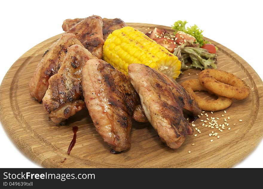 Chicken wings with sweet corn on a wooden plate