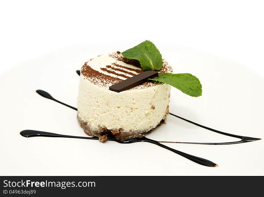 Creamy dessert is decorated with mint on a white plate. Creamy dessert is decorated with mint on a white plate