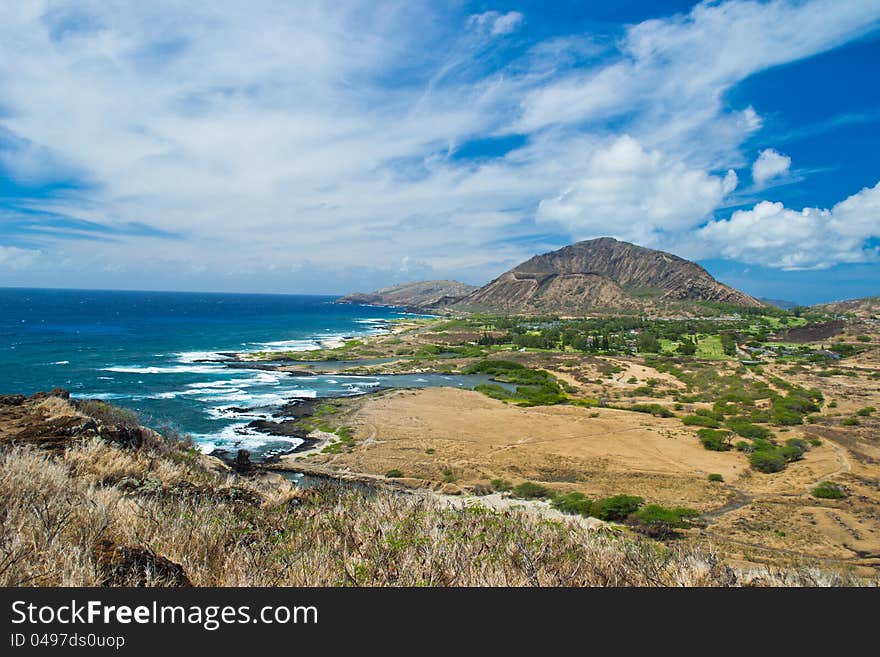 Aerial of Pacific ocean and Hawaii coast with waves hitting rocks. Diamond's Head on the background and blu sky with cloud strips. Aerial of Pacific ocean and Hawaii coast with waves hitting rocks. Diamond's Head on the background and blu sky with cloud strips.