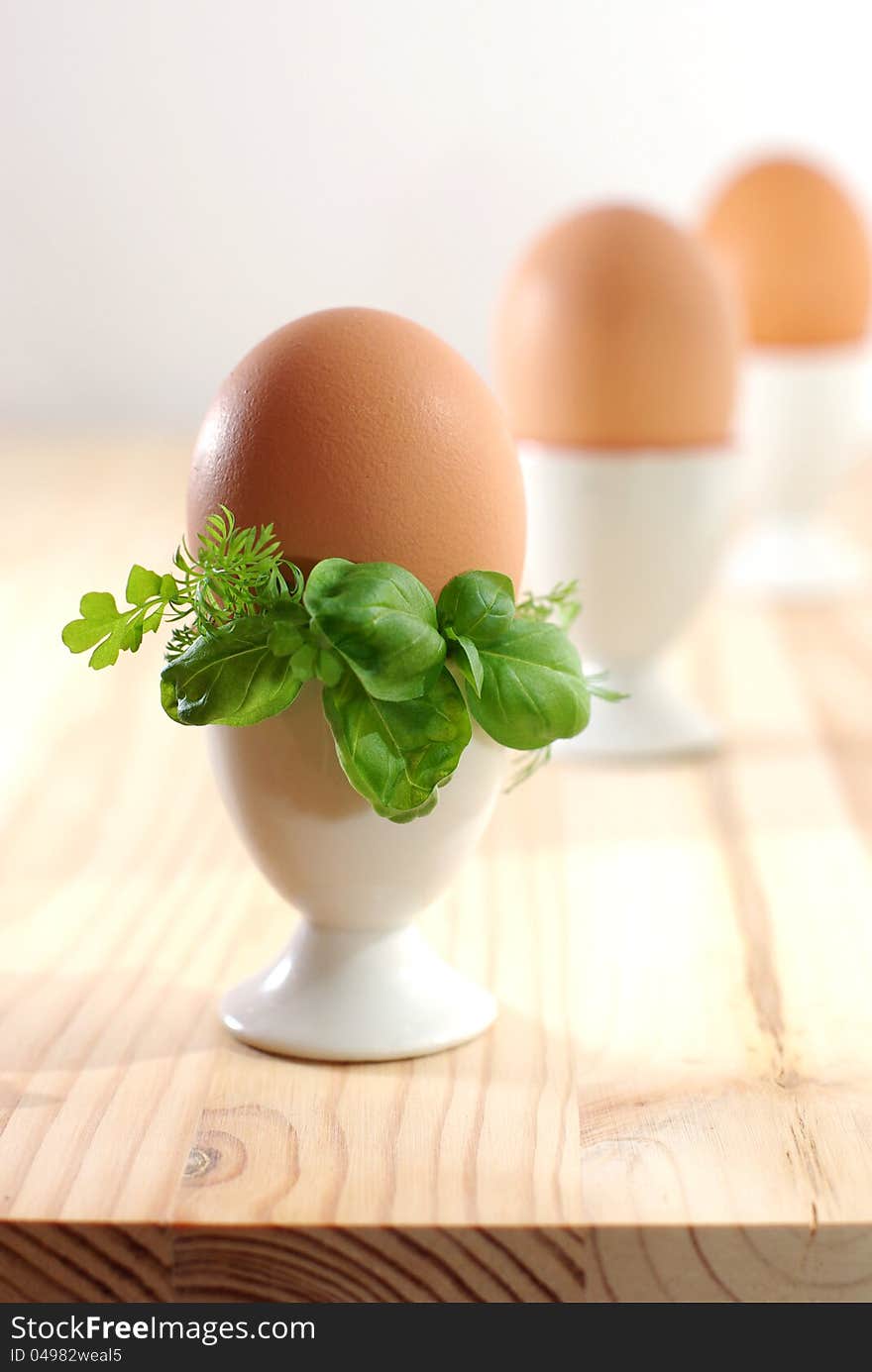 Egg in eggcup on the wooden desk, decorated with greenery. Egg in eggcup on the wooden desk, decorated with greenery