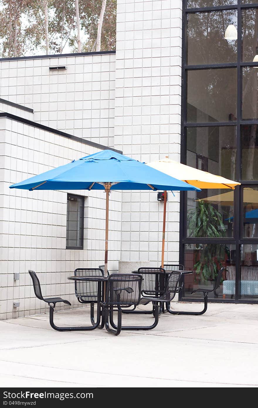 Patio furniture at outdoor cafe with blue and yellow umbrella