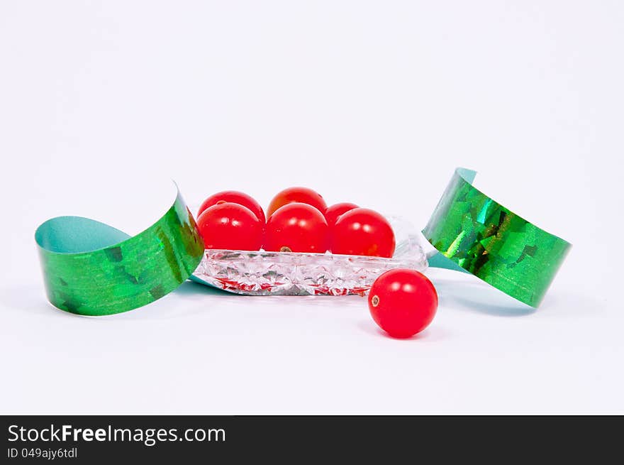 Little red tomatoes, green ribbon, in a small crystal vase on white. Little red tomatoes, green ribbon, in a small crystal vase on white.