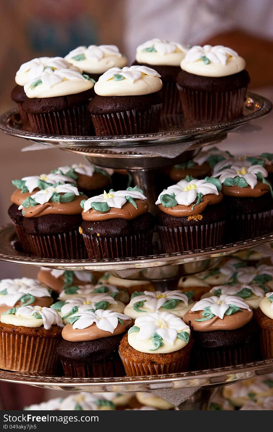 Miniature chocolate cupcakes with a flower shaped frosting design on display. Miniature chocolate cupcakes with a flower shaped frosting design on display