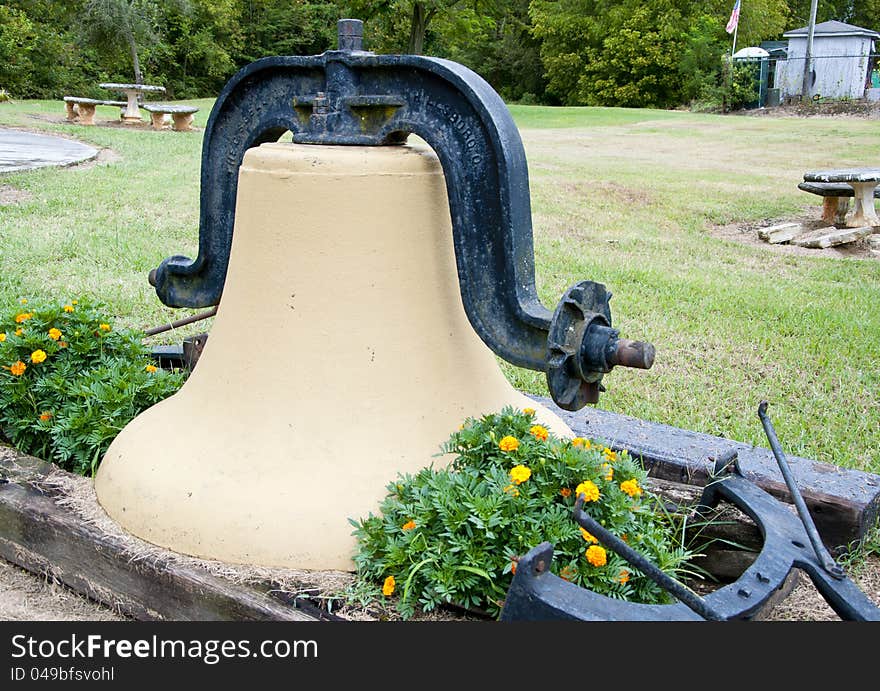 A old heavy liberty bell rests in a flower bed. A old heavy liberty bell rests in a flower bed.