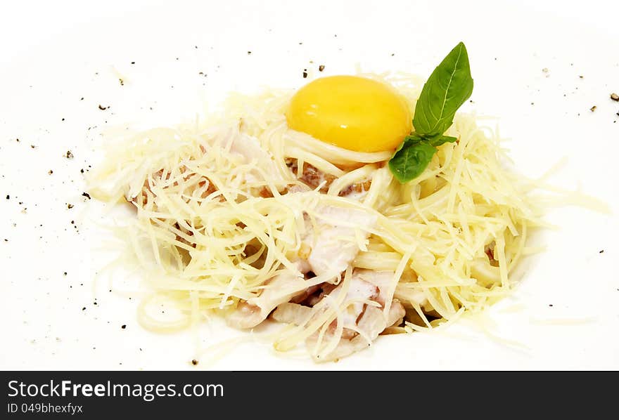 Spaghetti with egg and greens on a white plate