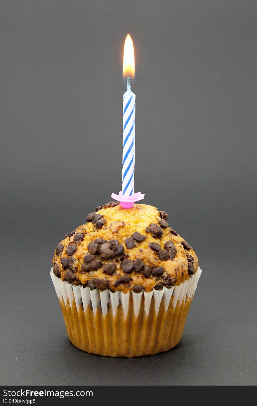 Delicious chocolate cupcake with a lit candle and the black background