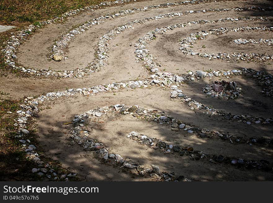 Looking down on a stone and sea shell maze or labyrinth with dirt paths. Looking down on a stone and sea shell maze or labyrinth with dirt paths