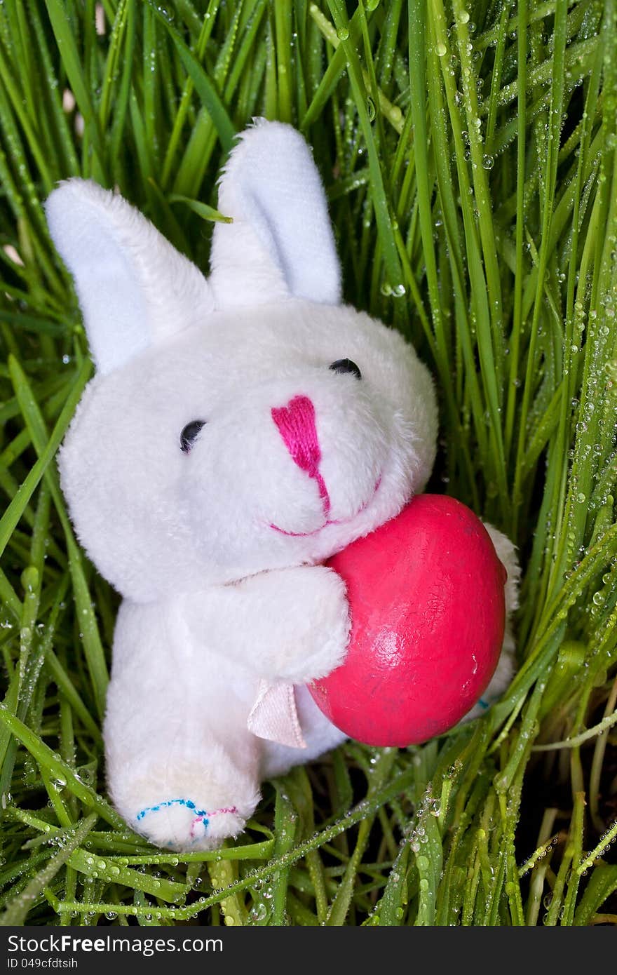 Bunny holding an Easter egg on green grass background