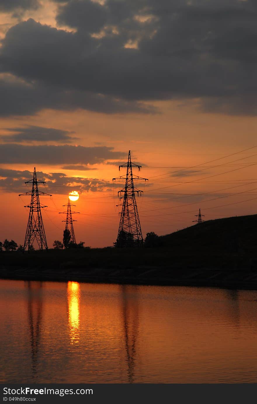 Sunset on the river. electricity power line.