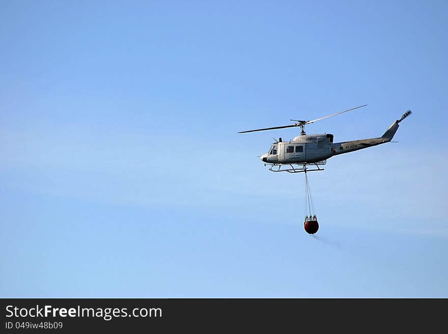 Firefighter helicopter in mission. Background of blue cloudy sky