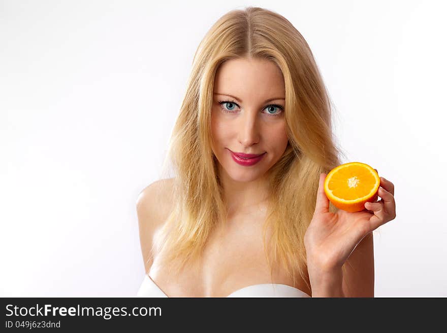 Closeup of young, blond, fit, beautiful caucasian woman with white bra holding half orange. Closeup of young, blond, fit, beautiful caucasian woman with white bra holding half orange