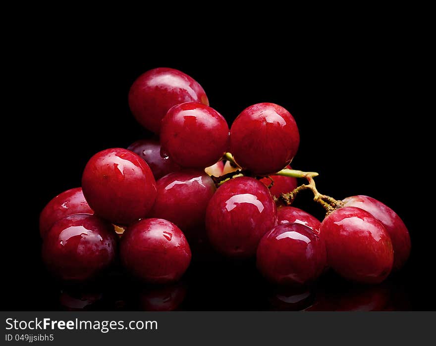 Bunch of red grapes on a black background with water drops