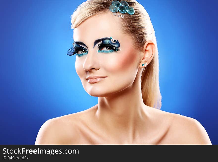 Beautiful blonde with artistic makeup over blue background