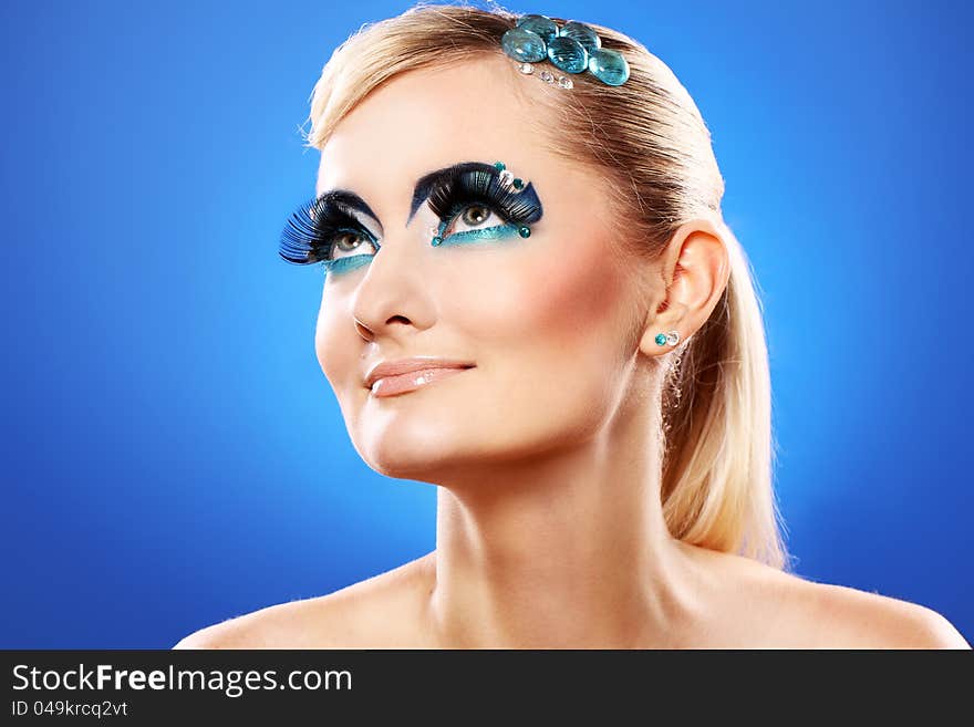 Beautiful blonde with artistic makeup over blue background