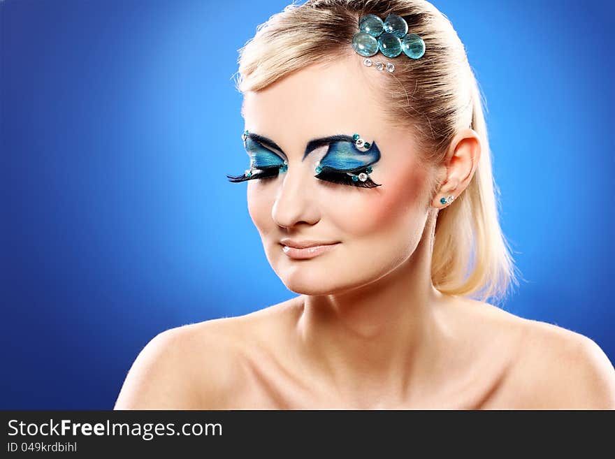 Beautiful blonde with artistic makeup over blue background