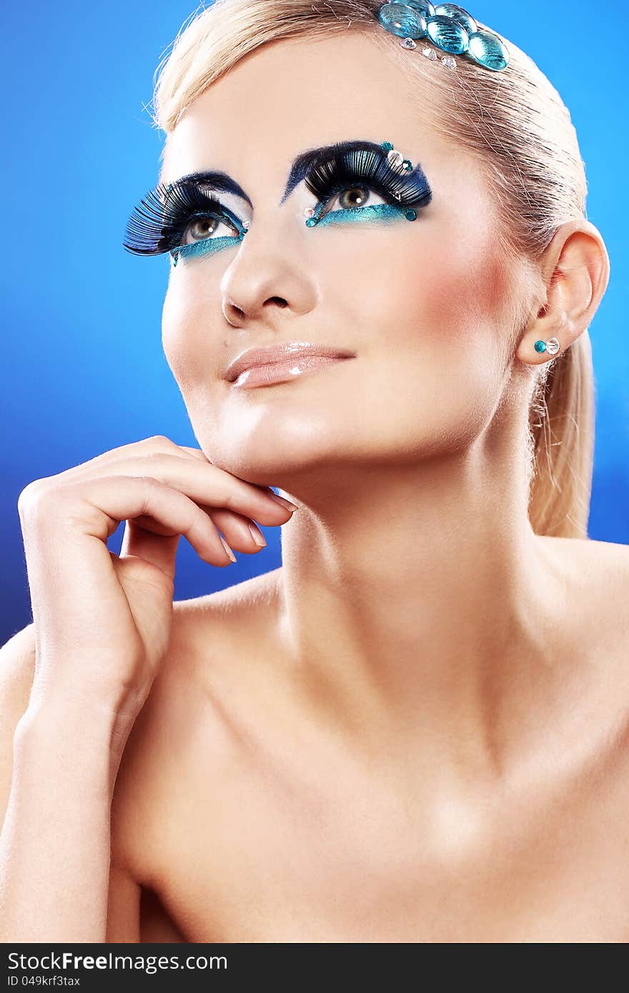 Beautiful blonde with artistic makeup over blue background