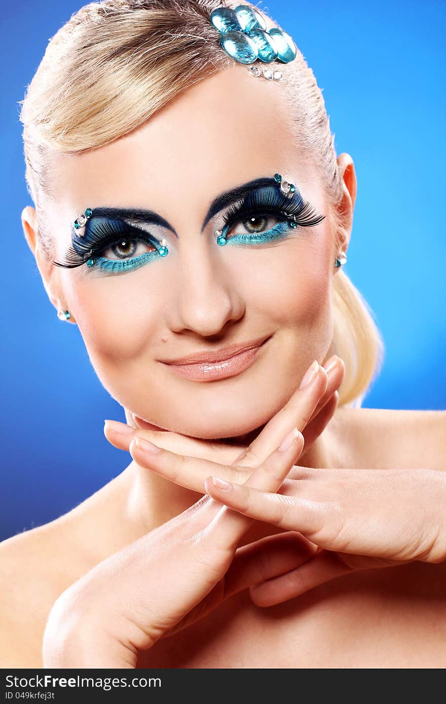 Beautiful blonde with artistic makeup over blue background