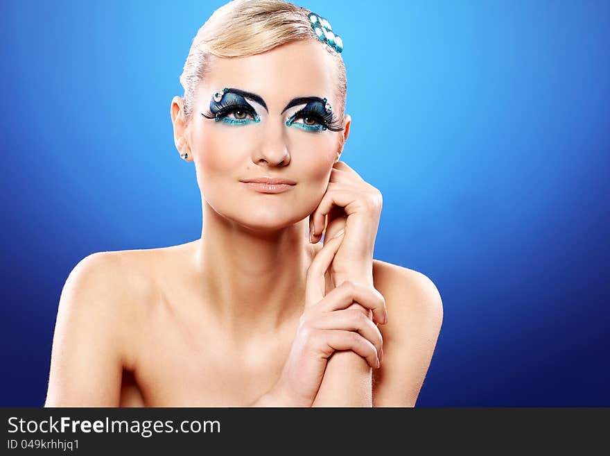 Beautiful blonde with artistic makeup over blue background