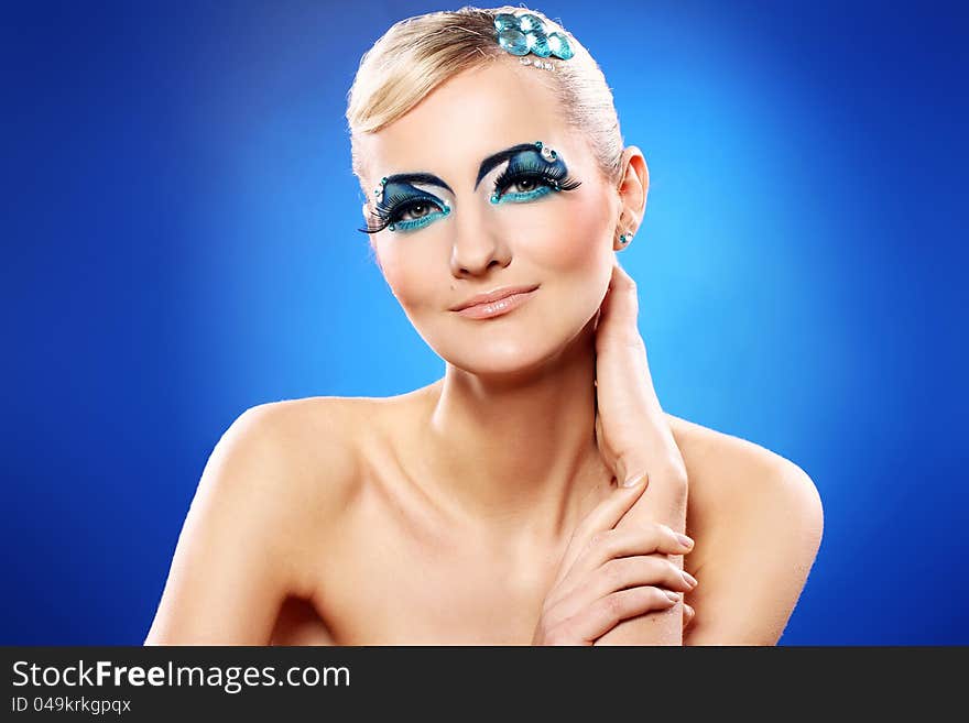 Beautiful blonde with artistic makeup over blue background