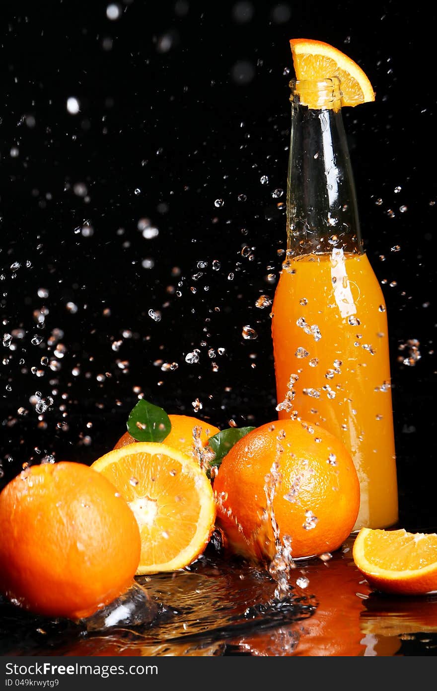 Fresh orange drink with splashes of water over black background