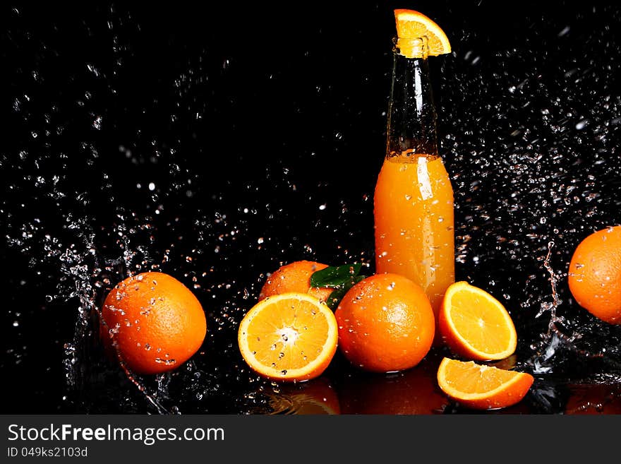 Fresh orange drink with splashes of water over black background