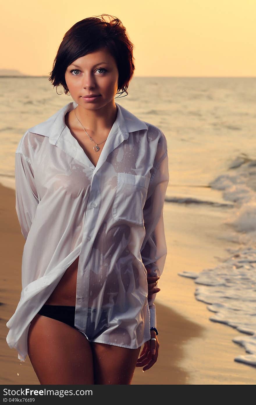 Portrait of a beautiful young brunette girl on the beach early in the morning at sunrise