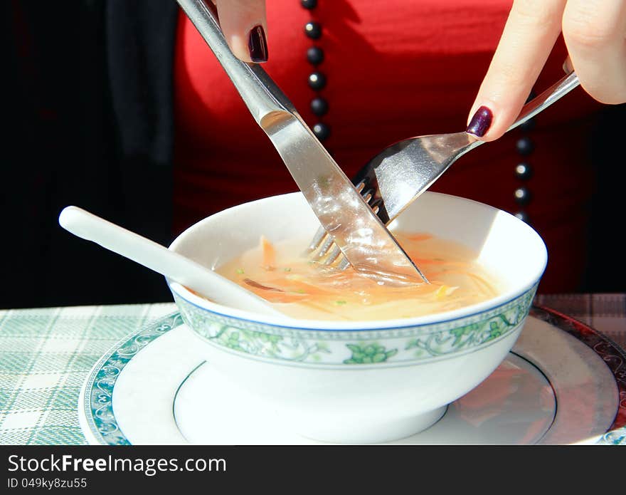 Woman eating healthy soup. Detail of her hands and a soup in the cup.