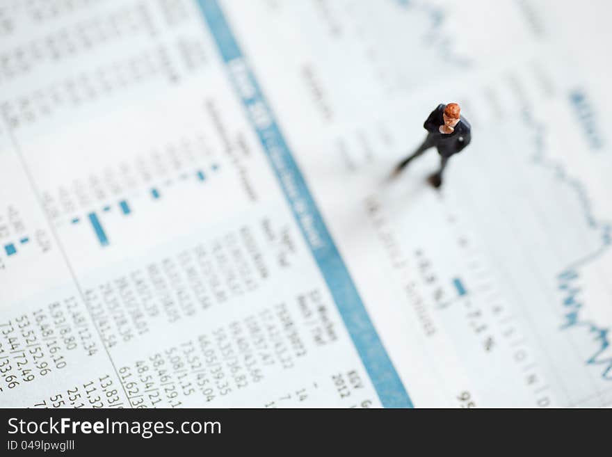 Conceptual picture of abusinessman figure standing on a stock chart on financial pages from a newspaper. Conceptual picture of abusinessman figure standing on a stock chart on financial pages from a newspaper