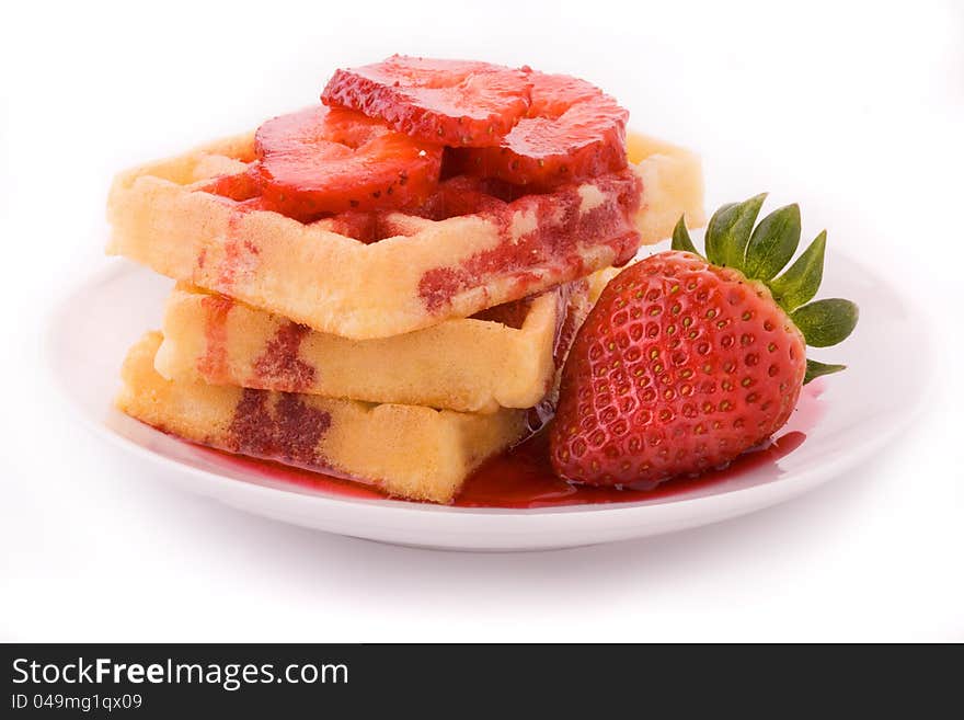 The group of waffles with strawberries on the plate situated on the white background. The group of waffles with strawberries on the plate situated on the white background