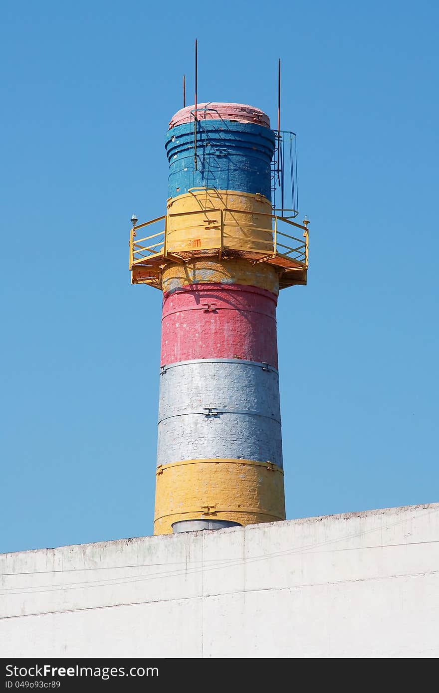 Painted brick chimney with a ladder against the blue sky. Painted brick chimney with a ladder against the blue sky