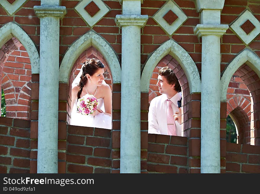 Happy bride and groom in windows of brick wall in wedding walk