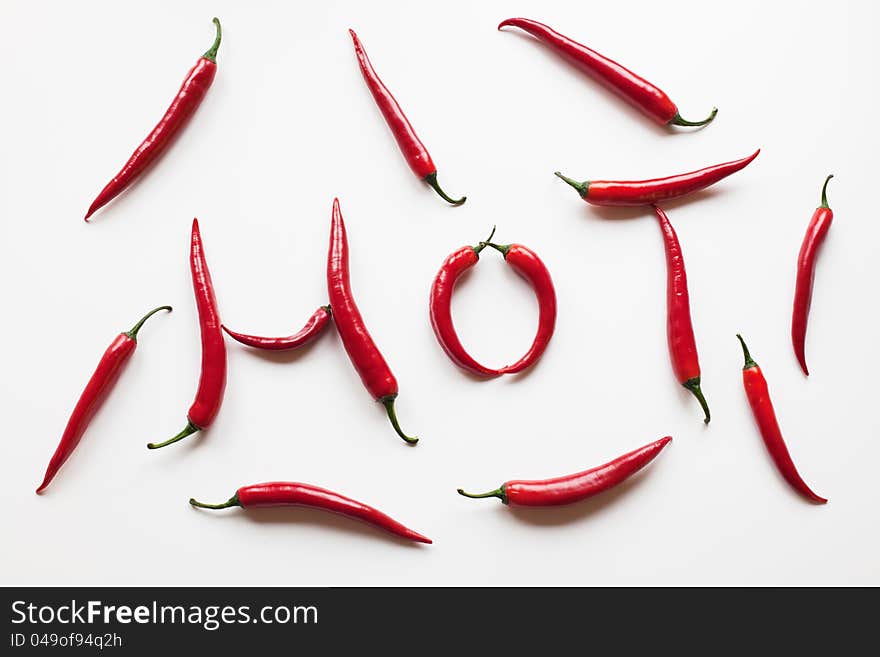 Hot red chili peppers isolated on white background while the peppers make the lettering HOT