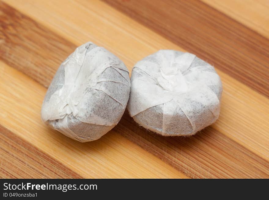 Two bricks of pu-erh tea wrapped on paper on bamboo background