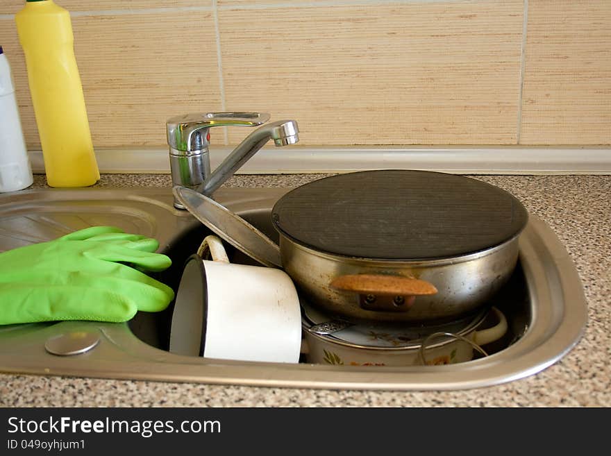 Pile of dirty dishes like plates, pot and cutlery in the sink. Pile of dirty dishes like plates, pot and cutlery in the sink