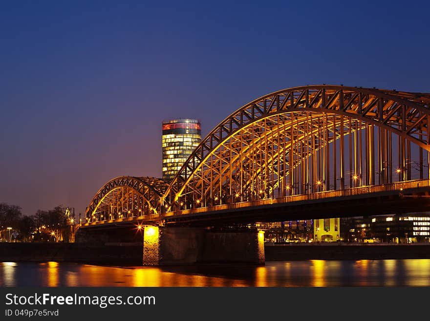 Night picture at the blue hour from Hohenzollern railway bridge in Cologne, Germany, with the rhine in the foreground and the LVR tower in the background. Night picture at the blue hour from Hohenzollern railway bridge in Cologne, Germany, with the rhine in the foreground and the LVR tower in the background