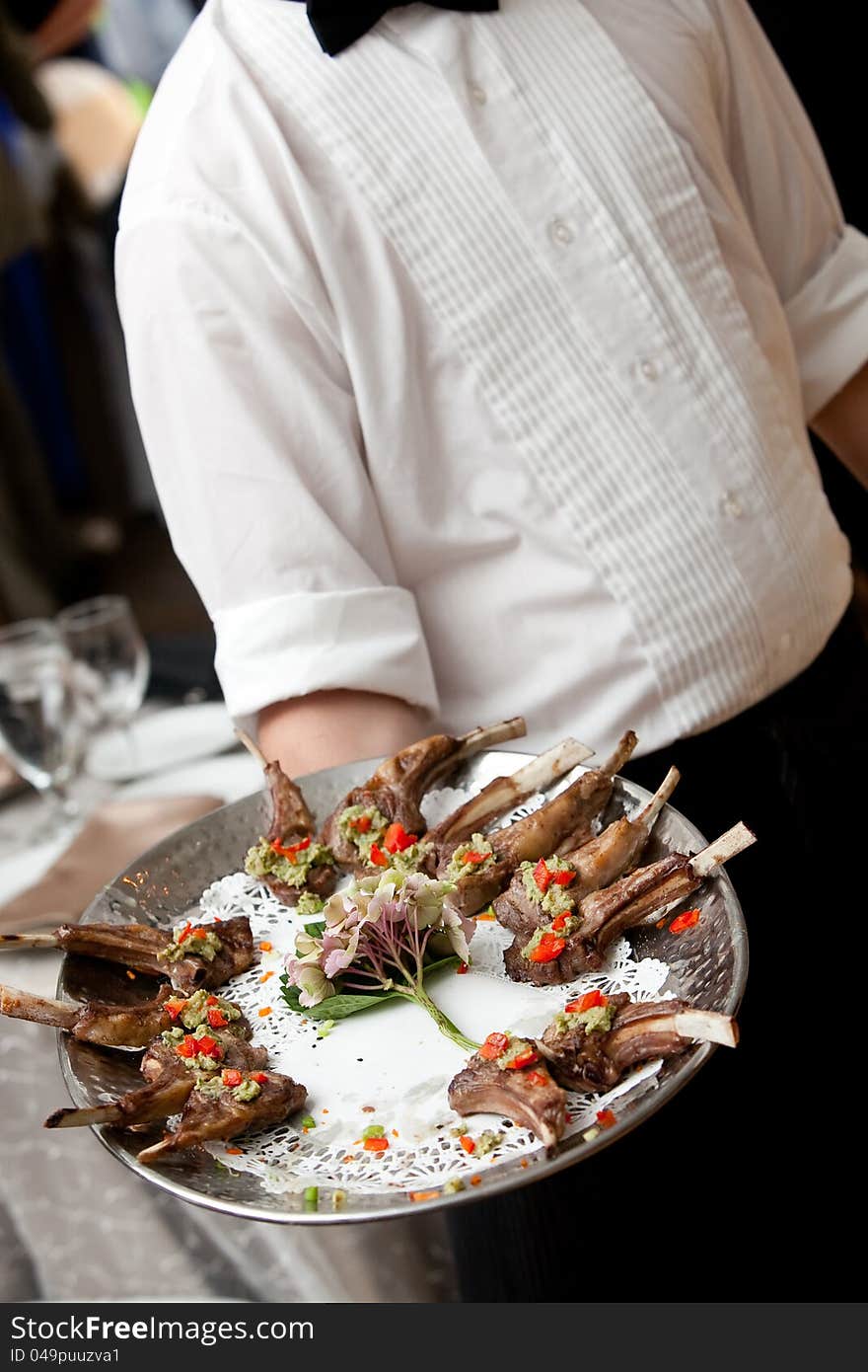 A waiter serving appetizers on a platter during a catered event. A waiter serving appetizers on a platter during a catered event