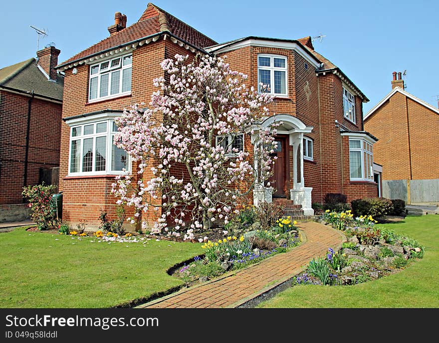 Photo of a picturesque kent cottage surrounded by a beautiful well manicured garden with a magnolia tree in full bloom taking centre stage. Photo of a picturesque kent cottage surrounded by a beautiful well manicured garden with a magnolia tree in full bloom taking centre stage.