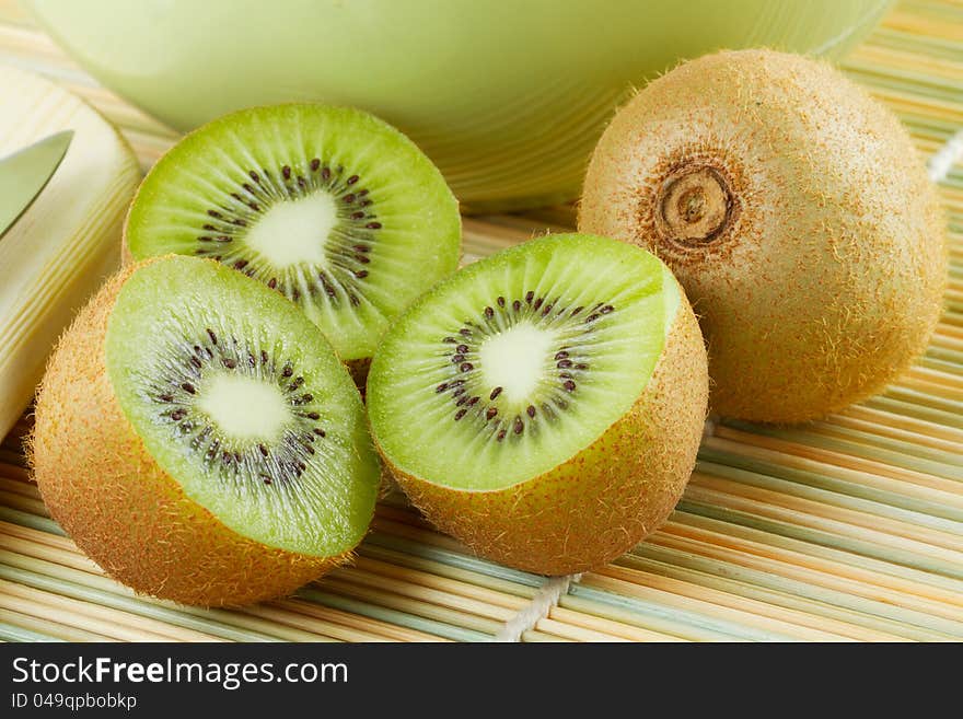 Kiwi sliced and whole fruits, green bowl on table