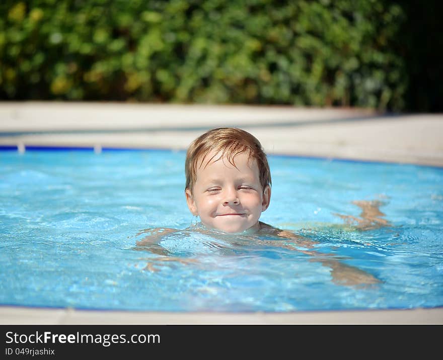 Outdoors in the pool the child swims. Outdoors in the pool the child swims