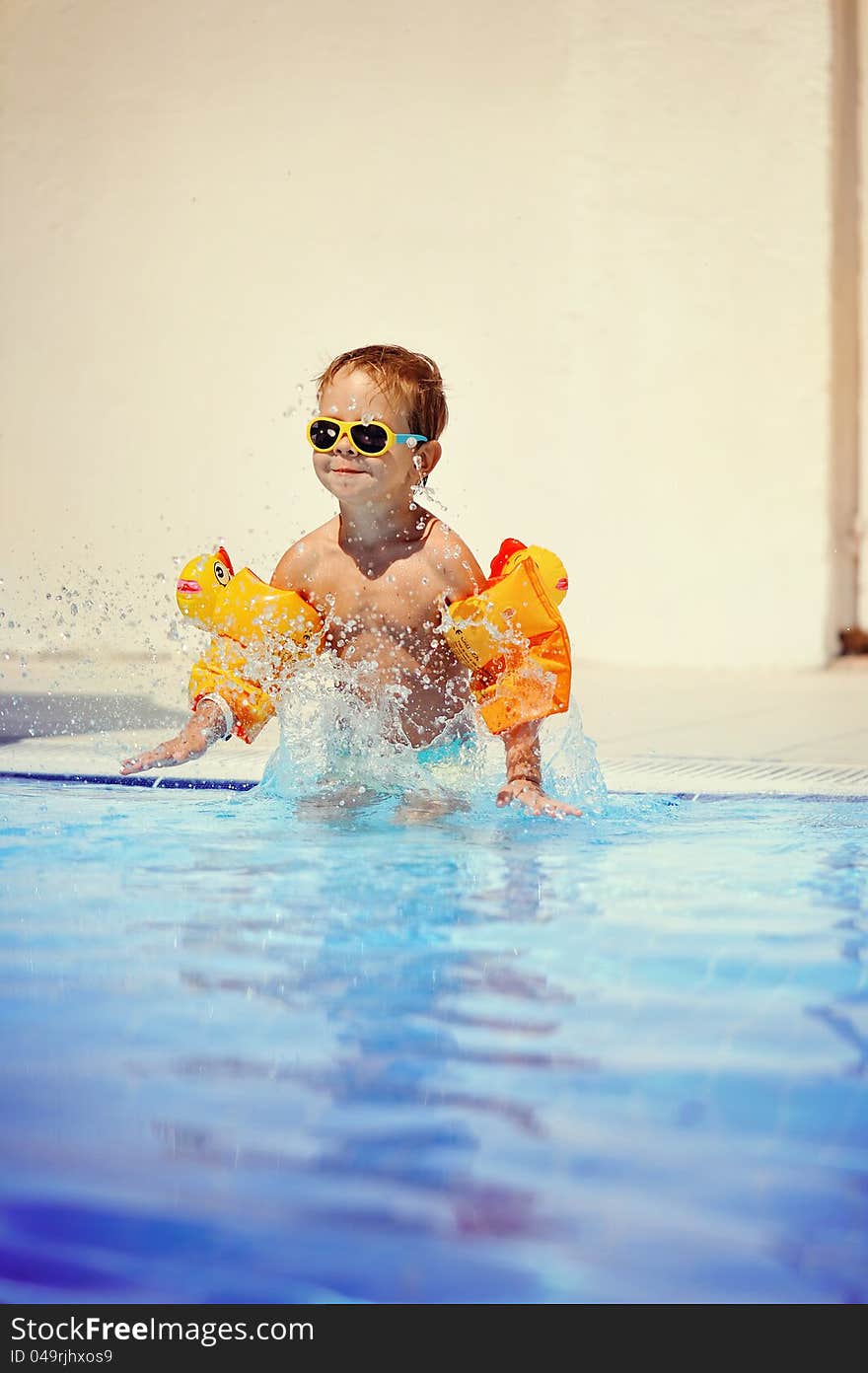 Outdoors in the pool the child swims. Outdoors in the pool the child swims